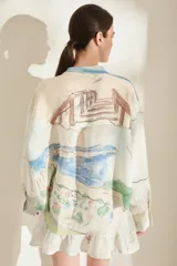 Camisa de lino italiano color crudo con estampado artístico de paisajes, cuello mao, manga larga, cierre frontal de botones y un bolsillo en el pecho.