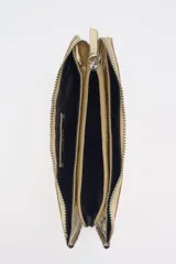 Cartera pequeña color dorado metálico con cierre superior. Presenta tachas plateadas decorativas a lo largo de los bordes superior e inferior.