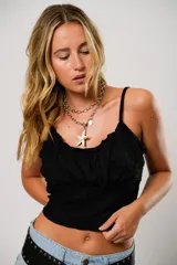 Top negro con breteles finos, escote recto con frunce y corte crop.