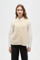 Chaleco sin mangas de tejido de punto con textura suave, cuello redondo y cierre frontal de botones a tono.