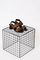 Sandalias con estampado animal print, con dos tiras anchas sobre el empeine y tira trasera con hebilla. El taco es cuadrado y de color negro brillante.