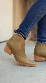 Botineta estilo texana de cuero color pistacho, con taco cuadrado de madera y punta fina. Presenta costuras decorativas en el empeine y cierre lateral interno.