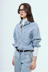 Camisa de denim de corte oversize, color celeste, con bolsillos frontales con solapa y botones metálicos.