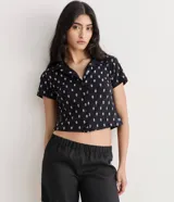 Camisa de manga corta color turquesa, confeccionada en tela de encaje con diseño floral. Presenta cuello camisero y cierre frontal con botones.