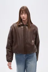 Campera estilo bomber de eco-cuero negra, con cuello camisero, cierre frontal y puños y cintura ajustados con elástico.