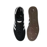 Championes Adidas modelo Handball Spezial, de diseño clásico con exterior de gamuza negra, tres bandas laterales blancas y suela de goma color caramelo. Incluye el nombre del modelo en letras doradas en el lateral.