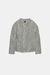 Chaqueta cruzada de estructura en tejido tweed de mezcla de hilos en tonos blanco y negro, con escote en pico, manga larga y cierre frontal con botones a presión ocultos.