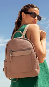 Mochila color rosa nude de símil cuero, con bolsillo frontal con cierre, asa de mano y correas regulables.