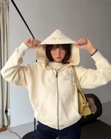 Campera con cierre frontal de Nude Project, confeccionada en algodón de alto gramaje con diseño oversized. Presenta capucha, bolsillos tipo canguro y un parche bordado con las iniciales NP en el pecho.
