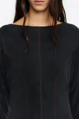 Vestido midi de cupro color negro, con corte línea A y vuelo. Cuenta con escote barco, manga larga y costuras con pespuntes decorativos a contraste.