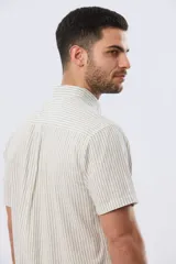 Camisa de manga corta confeccionada en mezcla de lino y algodón, con diseño de rayas verticales en tonos celeste y blanco. Cuenta con cuello camisero, botonadura frontal y bordado sutil en el pecho.