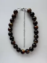 Collar corto compuesto por cuentas esféricas grandes con efecto marmolado en tonos marrones y dorados, con cadena de extensión plateada y cierre de mosquetón.