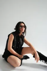 Vestido corto de jean color gris oscuro con efecto acid wash, sin mangas, con cuello camisero y cierre frontal de botones. Incluye dos bolsillos en el pecho con solapa y pespuntes decorativos.