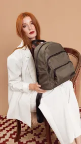 Mochila de diseño funcional en color verde militar, confeccionada en nylon impermeable. Cuenta con un compartimento principal amplio, un bolsillo secundario y un bolsillo frontal, todos con cierre. Incluye correas ajustables y manija superior reforzada.