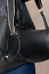 Cartera bandolera color chocolate con textura granulada, que incluye un monedero circular desmontable sujeto a la correa. Posee cierre superior y correa ajustable con detalles en color crema.