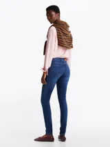 Pantalón jean skinny de tiro medio, color azul oscuro, con efecto desteñido en muslos y rodillas.