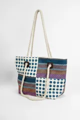 Bolso de playa o tote bag con diseño de patchwork en tonos rosados, naranjas y blancos. Presenta secciones con estampado de lunares rojos y secciones con tejido de rafia. Las asas son de cuerda trenzada.