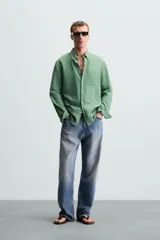 Camisa celeste a rayas verticales, de corte relaxed fit, confeccionada en lino y algodón. Tiene cuello abotonado, manga larga con puños abotonados, bolsillo de parche en el pecho y cierre frontal con botones.