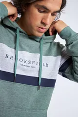 Canguro con capucha y cordón ajustable, de diseño color block en tonos verde, gris y azul marino. Presenta un bolsillo frontal tipo canguro y el logo de la marca bordado en el pecho.