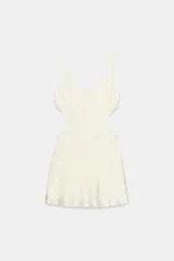 Vestido corto satinado de color blanco marfil, con escote redondo, tirantes finos y aberturas laterales tipo cut out.