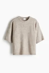 Remera de corte holgado en tejido de punto suave, color beige, con hombros caídos, mangas al codo y cuello redondo. Cuenta con remate acanalado en el cuello, puños y bajo.