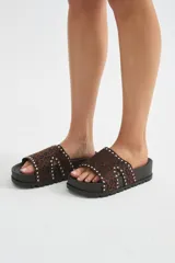 Sandalia plana con plataforma negra y tira ancha de pelo con estampado animal print tipo leopardo, decorada con tachas metálicas en los bordes.