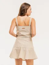 Falda corta color beige con rayas verticales blancas, corte evasé y volado en el ruedo.