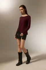 Remera de manga larga color bordó, confeccionada en viscosa, con cuello redondo y detalle de nudo lateral que genera un drapeado suave.