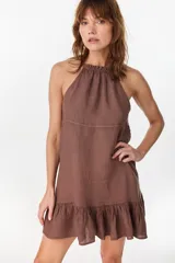Vestido corto marrón con cuello halter fruncido, corte suelto y falda con volados en el ruedo. Confeccionado en 100% lino italiano.