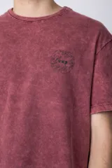 Remera de algodón con efecto de lavado desgastado tipo snow wash, de corte semi-oversize, cuello redondo y manga corta. Presenta un pequeño estampado gráfico circular en el pecho.