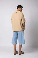 Remera de corte oversize confeccionada en tejido texturado tipo lino, de color beige, con cuello redondo amplio y mangas cortas de calce relajado.