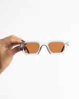 Lentes de sol con marco rectangular transparente azulado y lentes marrones.