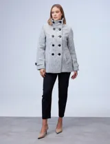 Tapado corto de lana y poliéster, con tejido tweed en tonos blanco y negro. Presenta cuello con solapa, doble abotonadura frontal en color negro y bolsillos verticales.