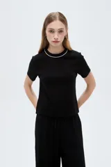 Remera negra de viscosa con cuello redondo decorado con una línea de strass, de mangas cortas y corte ajustado.