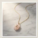 Collar de acero con baño de oro, compuesto por una cadena fina y un dije hexagonal de cuarzo rosa natural con una circonia rectangular engastada en el centro.