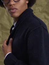 Cardigan de punto gris con cuello tipo chal y cierre frontal de botones. Presenta puños y ruedo acanalados, ofreciendo un diseño clásico y versátil.