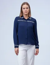 Camisa azul de gasa con cuello, delantera y puños con apliques de pasamanería.