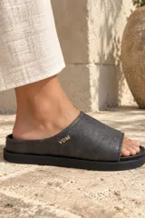 Sandalias tipo chinela Clog Dune de cuero gastado color gris oscuro, con suela plana y mini plataforma. Presenta detalle de iniciales VDM doradas en el lateral.