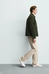 Pantalón jeans de corte recto y tiro medio, confeccionado en denim de algodón color beige con efecto lavado, bolsillos clásicos y cierre frontal con cremallera y botón.