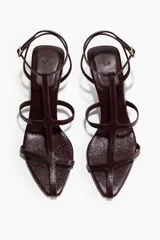 Sandalias de tiras finas color bordó, con efecto texturizado, taco cónico bajo y cierre de pulsera con hebilla metálica.
