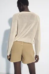 Falda pantalón cruzada de tiro medio en color tostado, con diseño estilo cargo que incluye bolsillos de parche con solapa y detalle de argolla metálica. Cuenta con trabillas y un cinturón integrado con hebilla metálica.