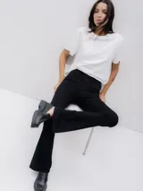 Pantalón de jean negro de tiro alto, corte ajustado en caderas y muslos, con pierna acampanada.