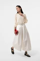 Pantalón wide leg de color blanco, de silueta amplia y gran movimiento, con pliegues delanteros que aportan volumen y estructura, y cintura definida.