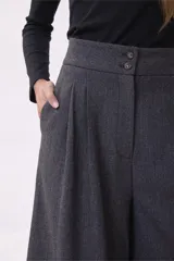 Pantalón de vestir de corte sastrero y pierna ancha (wide leg), confeccionado en tejido de lana gris. Presenta cintura alta con doble botón y pinzas frontales que aportan volumen y caída fluida.
