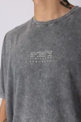 Remera gris de corte oversize con efecto acid wash y estampa pequeña en el pecho.