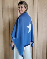 Ruana tejida en algodón, de color azul con un diseño de estrella grande en color blanco en la parte posterior y borde en tono azul oscuro.