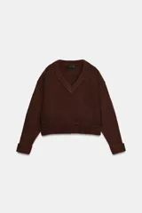Jersey de punto de color marrón con escote en pico, manga larga y diseño de corte ligeramente cropped. Presenta costuras marcadas y acabado acanalado en puños y bajo.