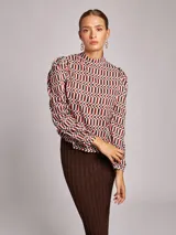 Blusa de viscosa con estampado geométrico multicolor, cuello subido y manga larga abullonada con frunces en los hombros.