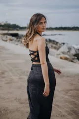 Top negro brillante con cuello halter y espalda descubierta con tiras cruzadas.