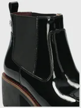 Botineta Chelsea Hush Puppies modelo Sula, color negro en acabado charol, con elásticos laterales y suela robusta con taco ancho.